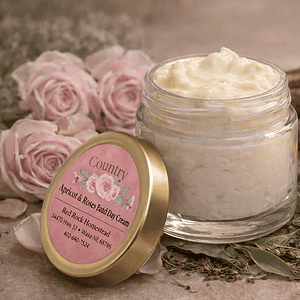 Natural apricot and rose facial cream in a glass jar with dried apricots and roses.